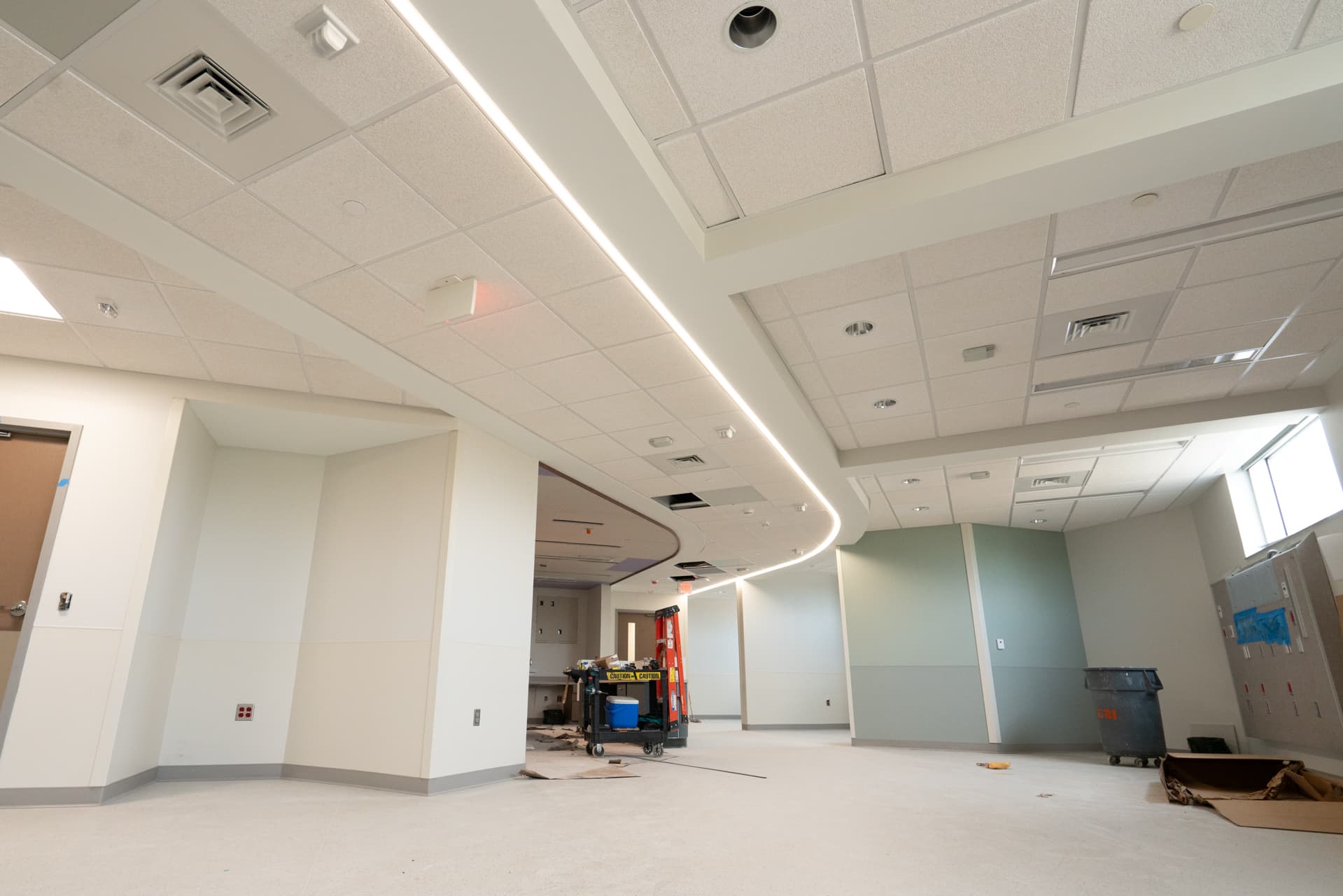 Suspended acoustical tile ceiling with recessed linear lighting along a finished corridor